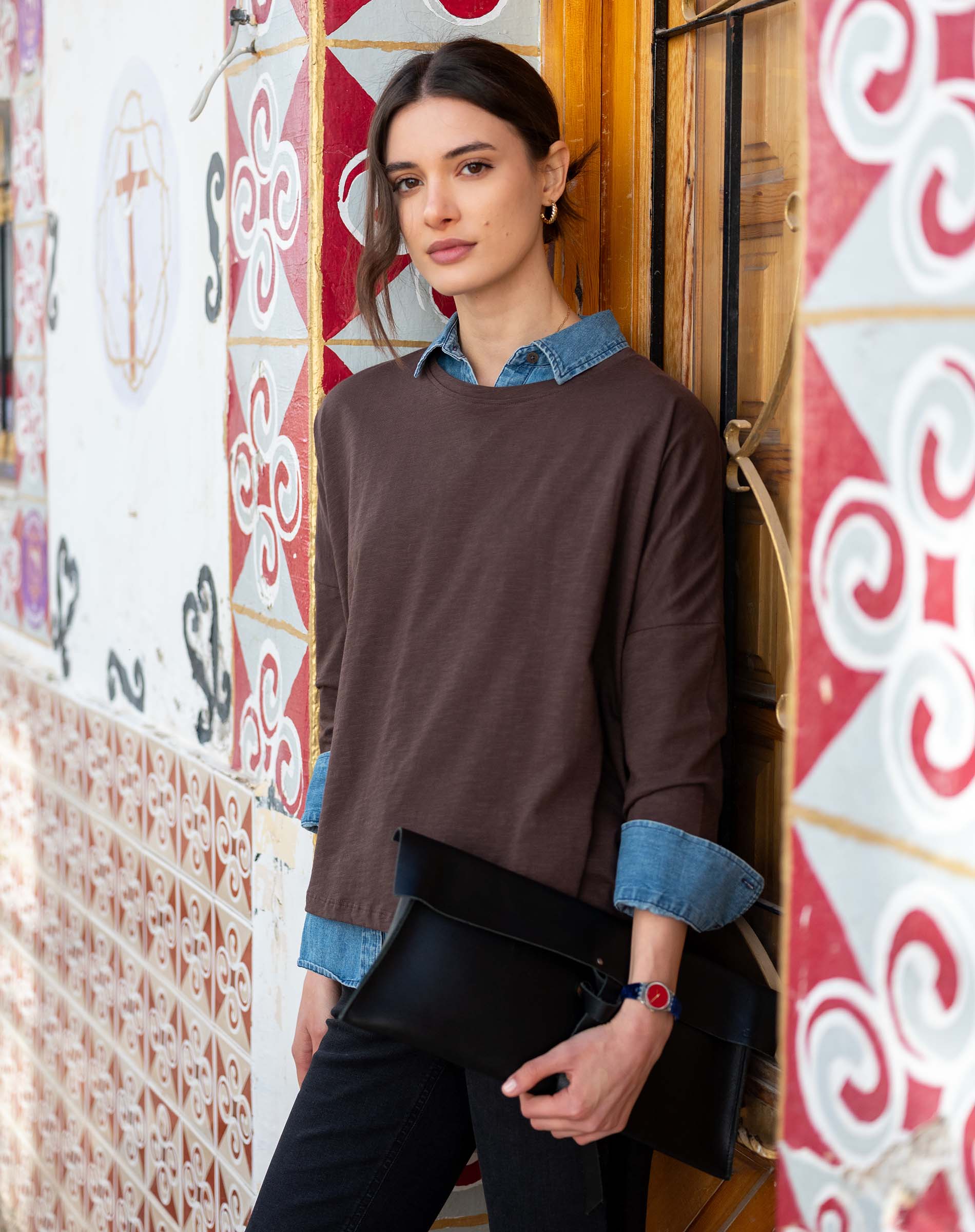 Model wearing the espresso-colored slub knit tee with a layered blue denim collar and dark pants.