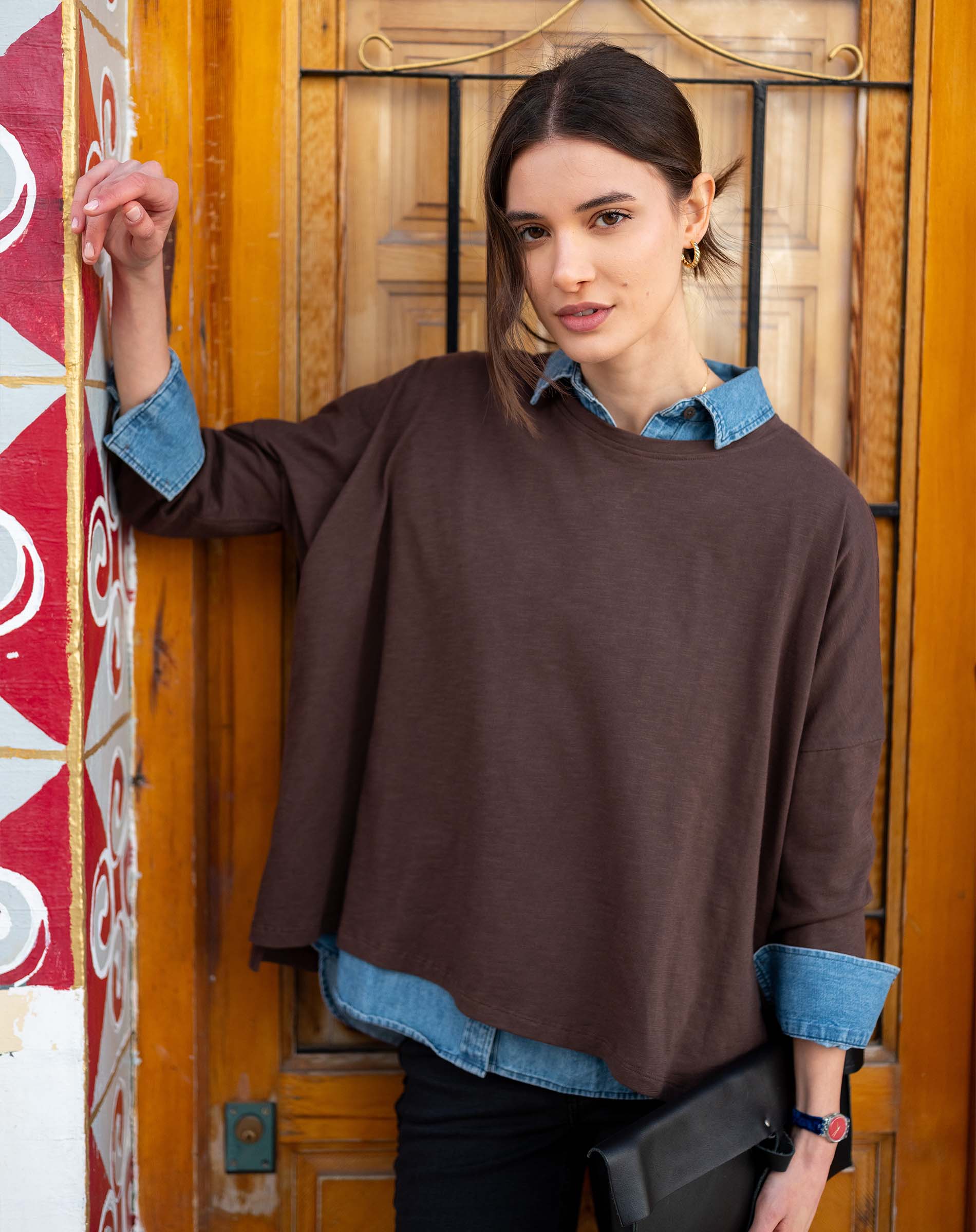 Espresso slub tee with a relaxed fit and long sleeves layered over a denim shirt.
