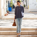 Model wearing an indigo slub knit tee with a relaxed fit and striped sleeves over light wash denim jeans.