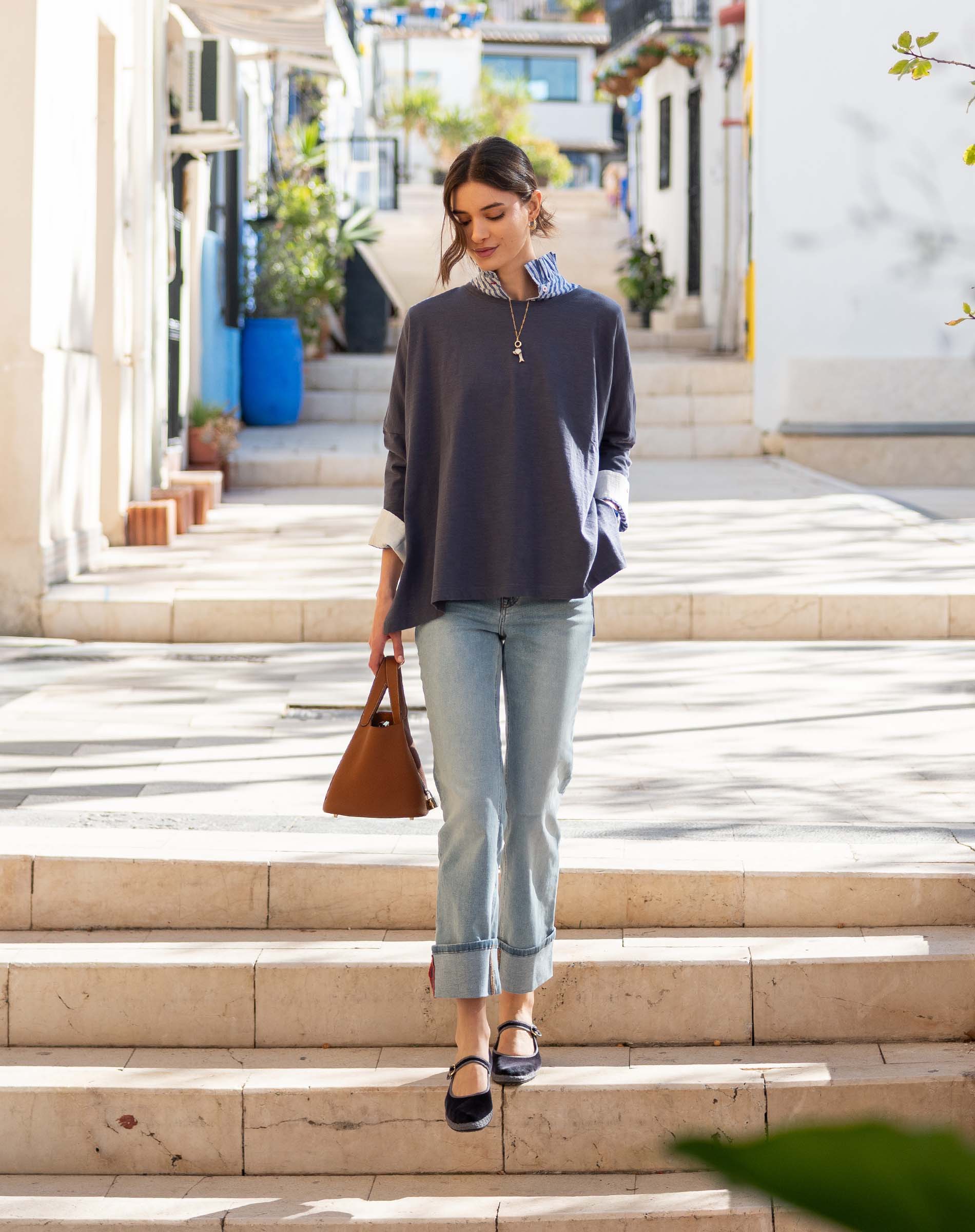 Model wearing an indigo slub knit tee with a relaxed fit and striped sleeves over light wash denim jeans.