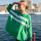 Woman wearing a green oversized shirt with white stripes by a waterfront