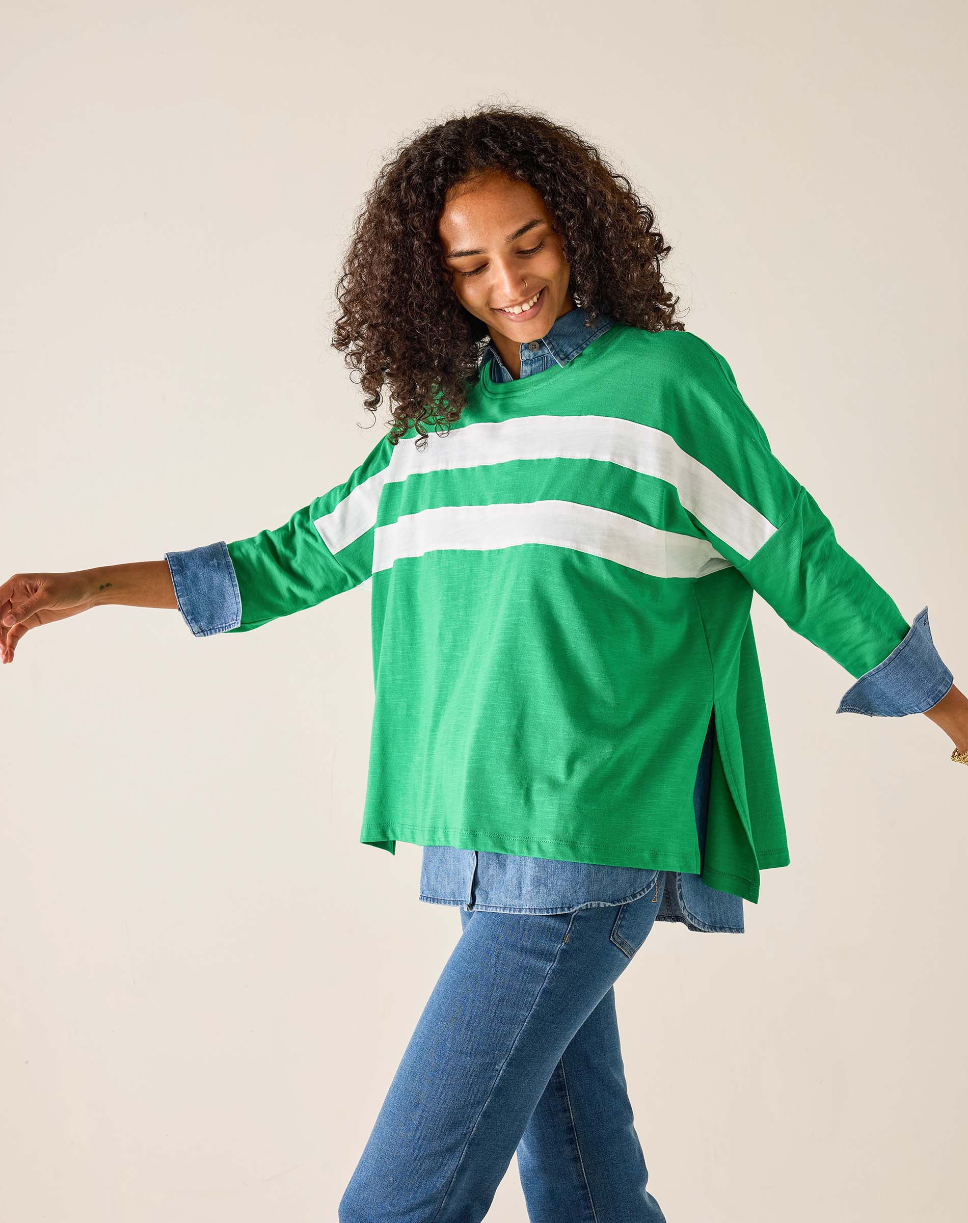 Woman wearing a green and white striped shirt with rolled-up sleeves on a beige background