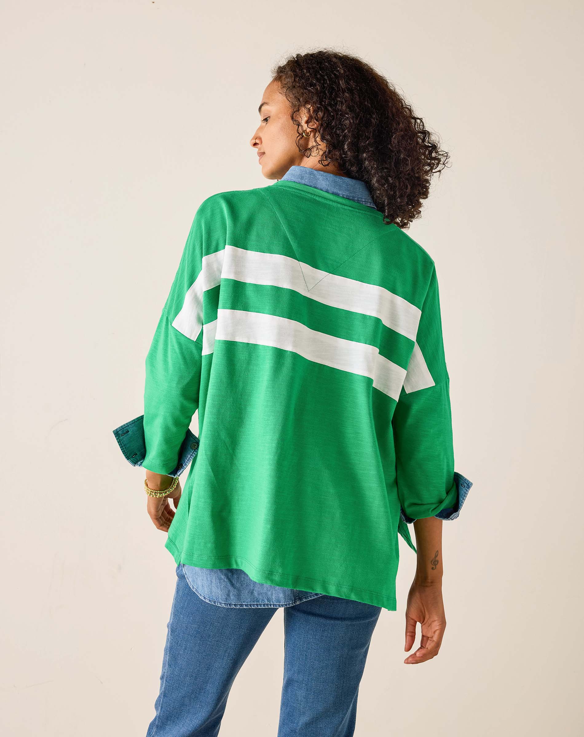 Person wearing a green jacket with white stripes on a beige background