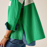 Green jacket with white stripes over a blue denim outfit on a neutral background