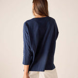 Person wearing a navy blue top and white pants on a beige background