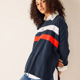 Person wearing a navy rugby shirt with red and white stripes on a beige background