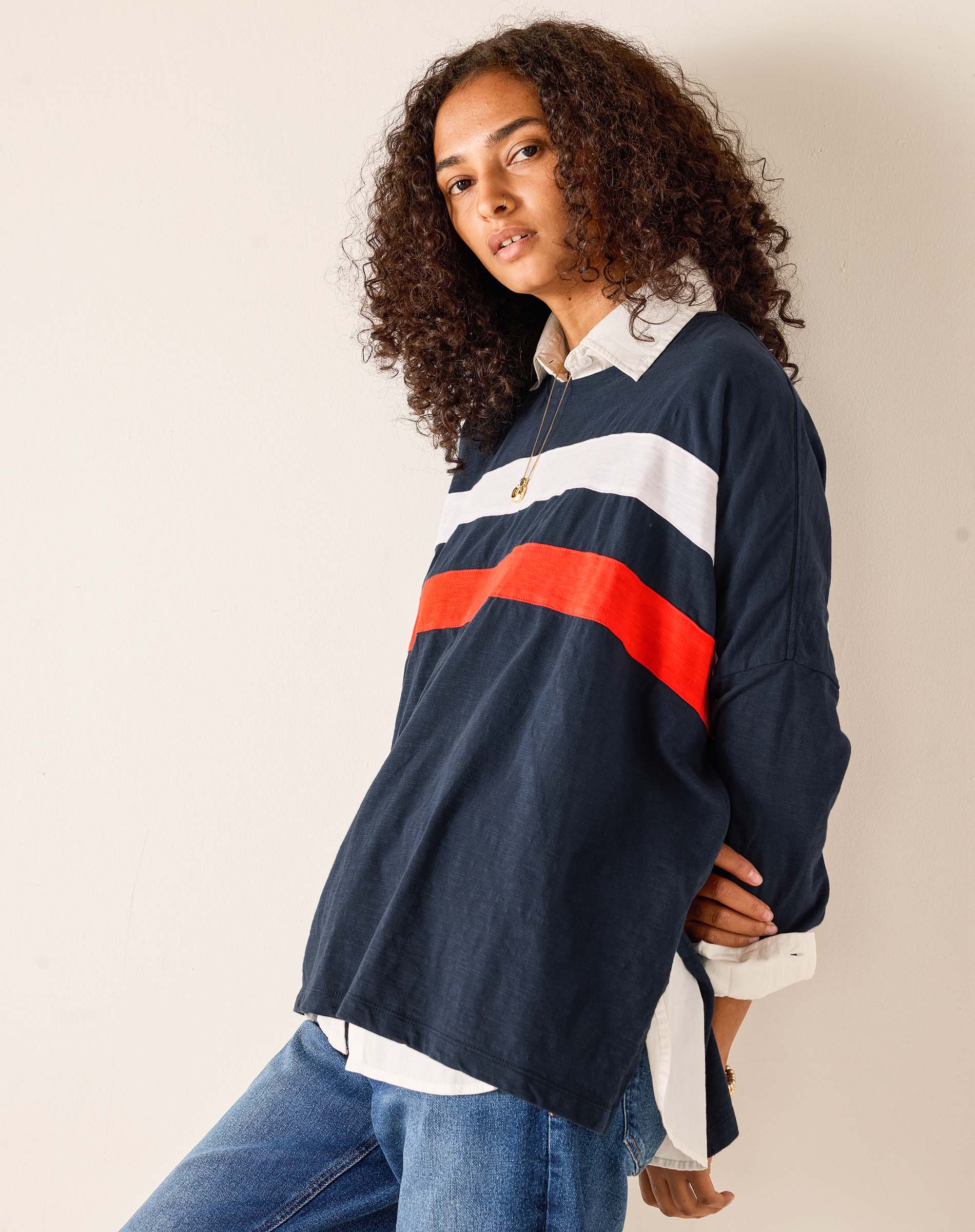 Person wearing a navy rugby shirt with red and white stripes on a beige background