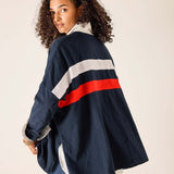 Person wearing a navy jacket with red and white stripes on a plain background