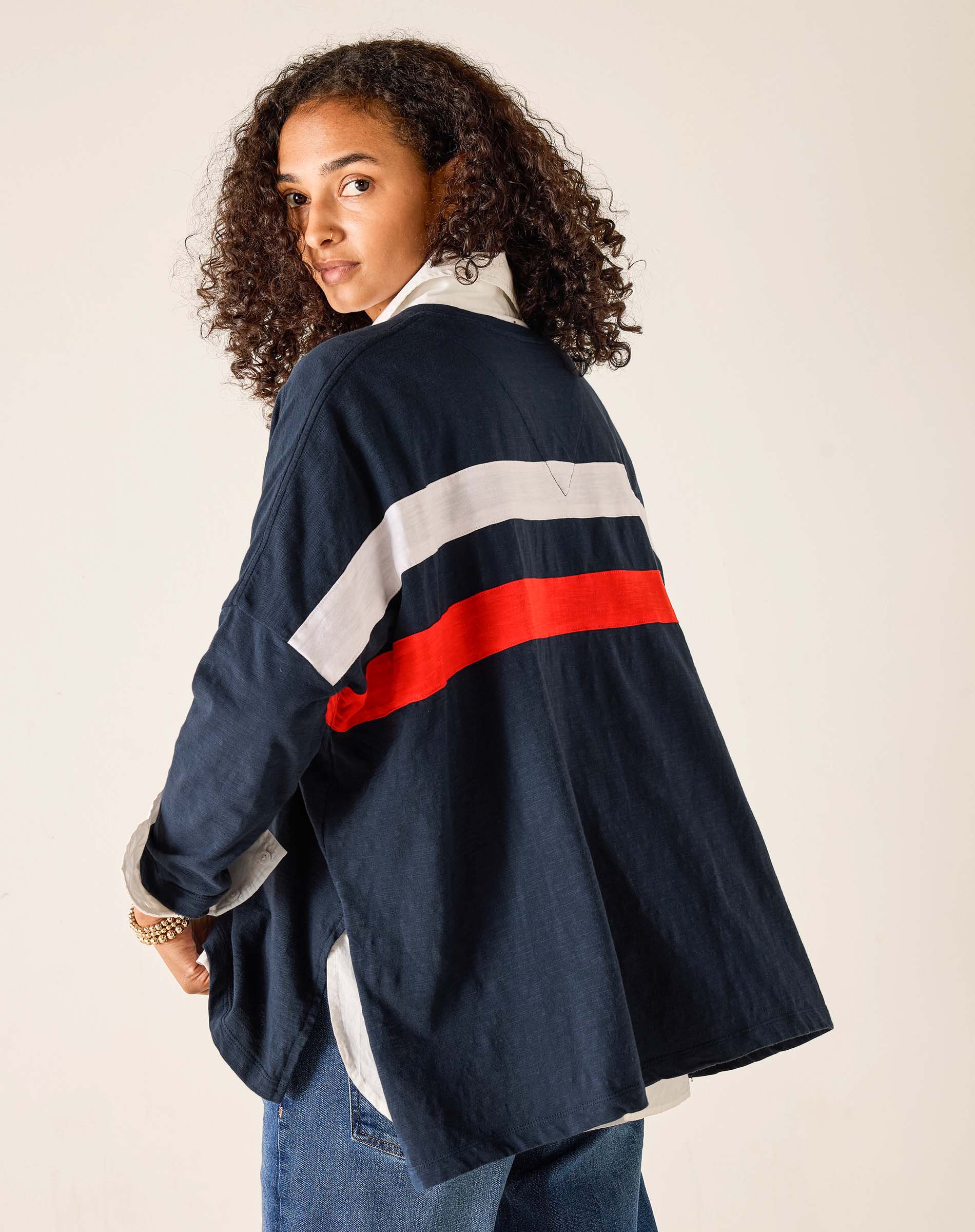 Person wearing a navy jacket with red and white stripes on a plain background