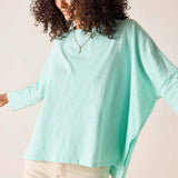 Woman wearing a light blue poncho against a beige background