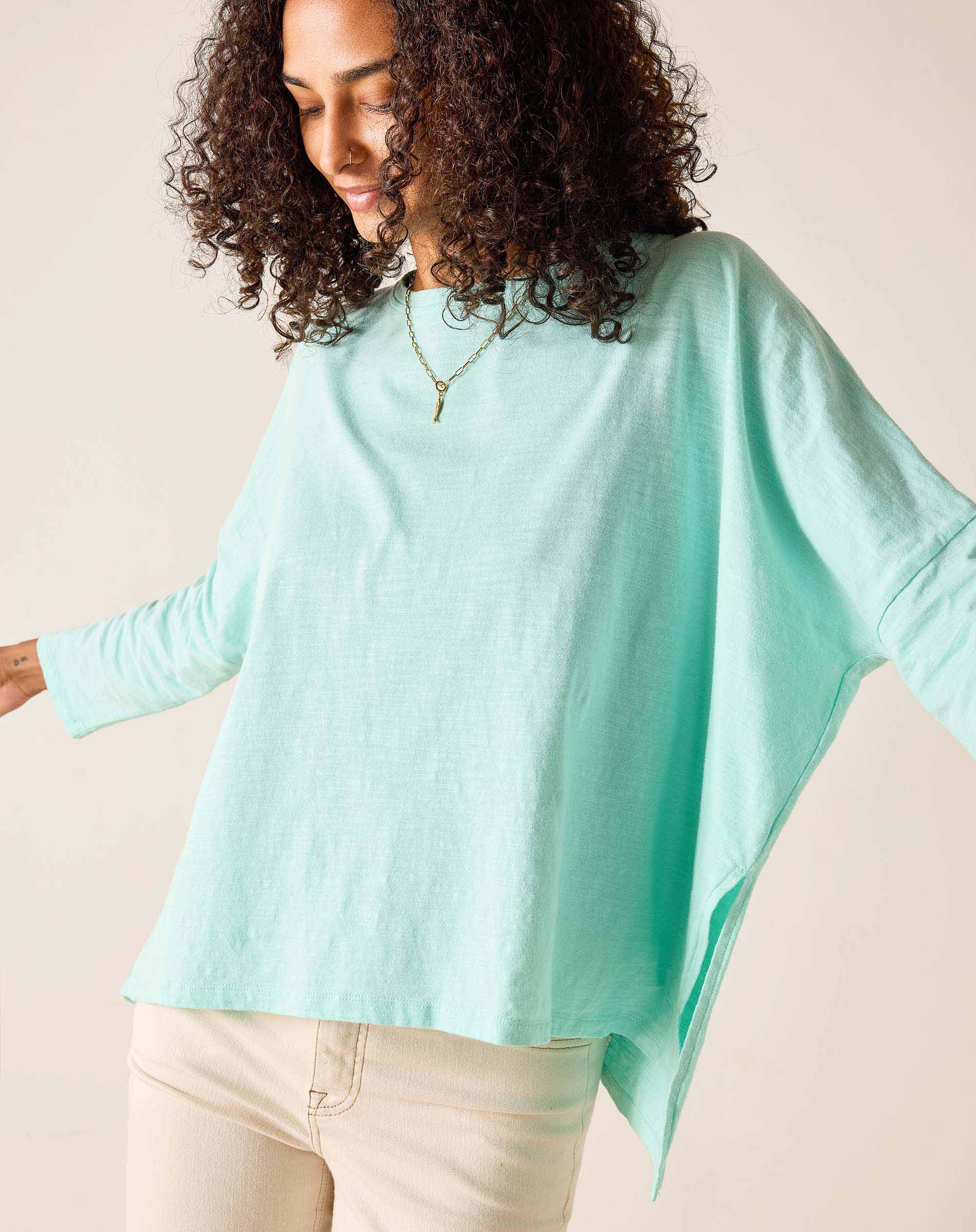 Woman wearing a light blue poncho against a beige background