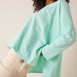 Person wearing a light blue sweater and beige pants against a plain background