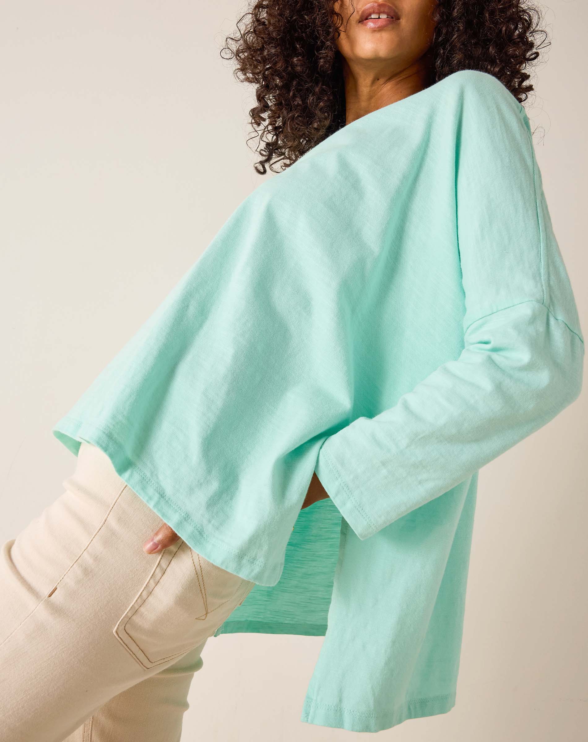 Person wearing a light blue sweater and beige pants against a plain background