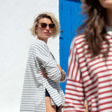 Woman in a striped shirt standing next to a blue door with another person in the foreground.