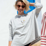 Woman wearing a striped shirt and sunglasses with a blue door in the background