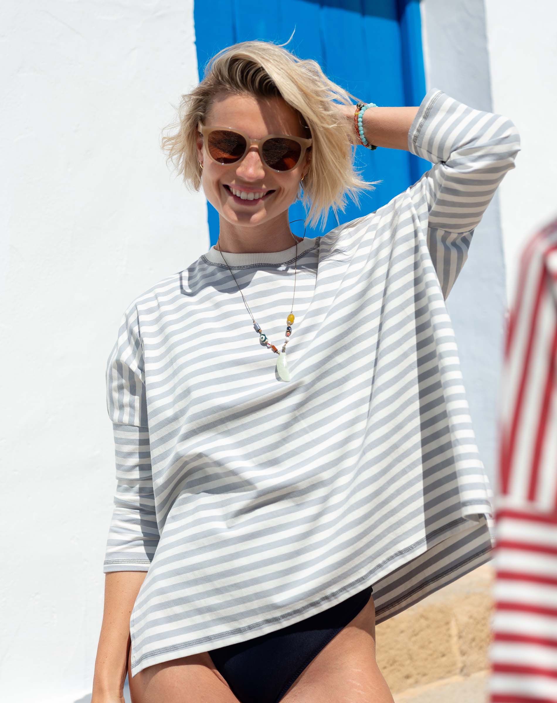 Woman wearing a striped shirt and sunglasses with a blue door in the background