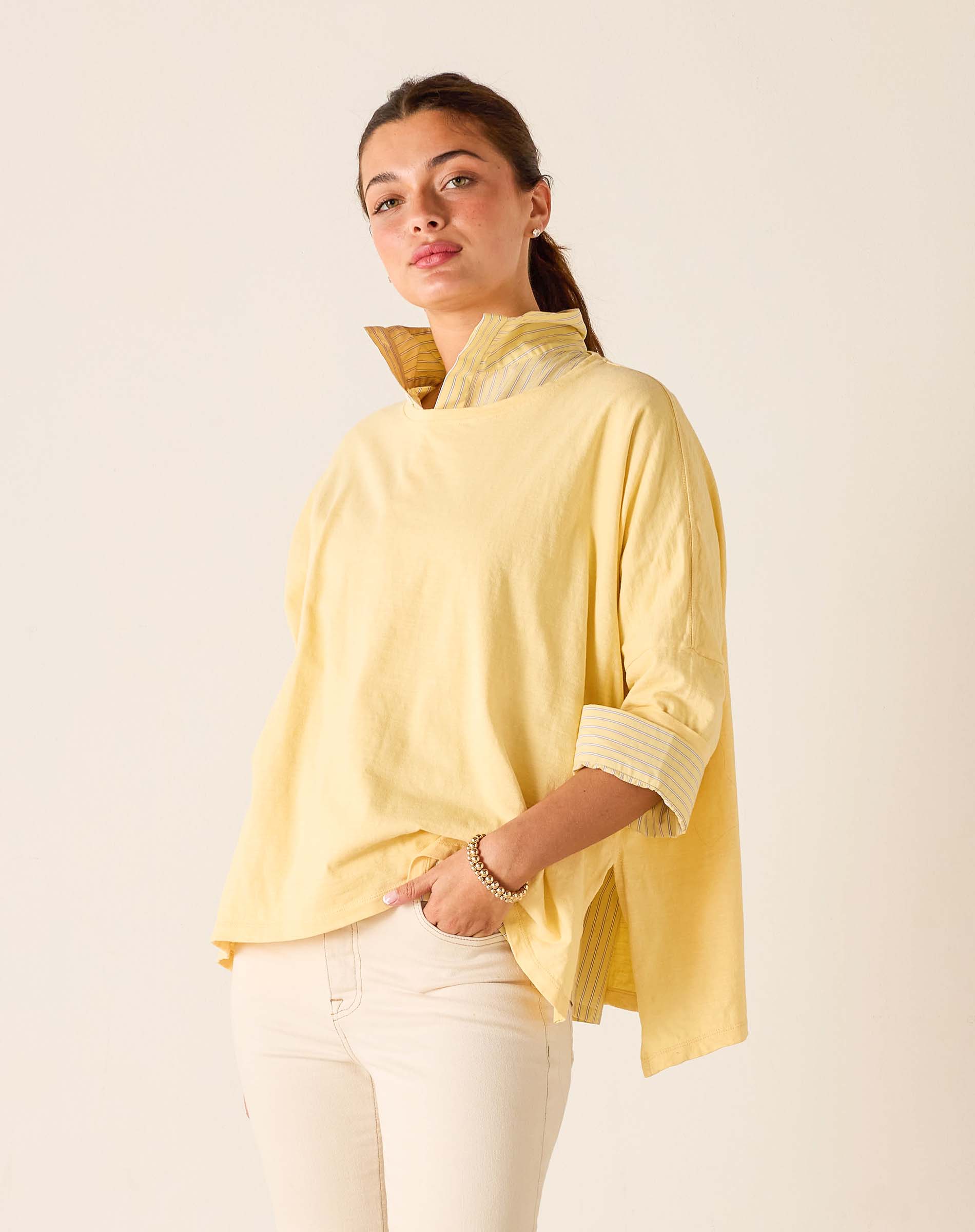 Woman wearing a yellow top with a high collar against a plain background