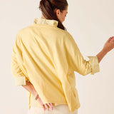 Person wearing a yellow shirt with rolled-up sleeves on a plain background