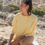 Woman in a yellow dress sitting on a rock with a natural landscape background