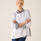 Woman wearing a white shirt with gray accents and blue jeans on a beige background