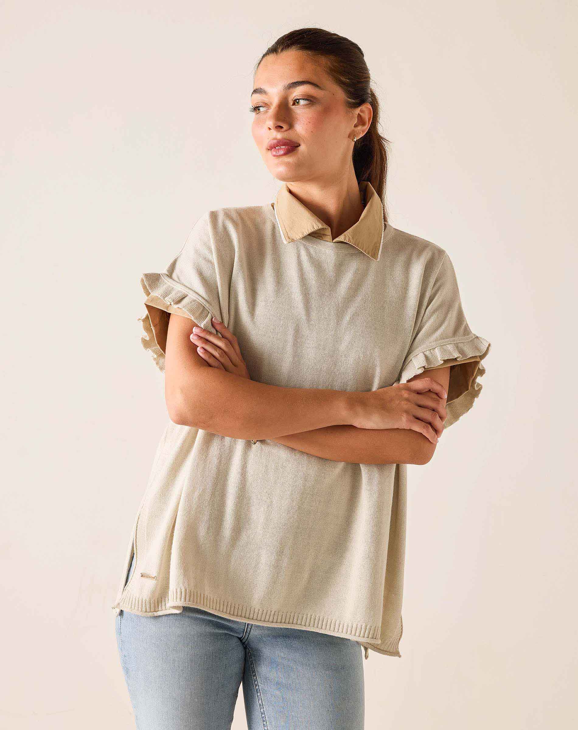 Woman wearing a beige sweater with a collar against a plain background