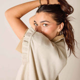 Woman wearing a beige sweater against a plain background