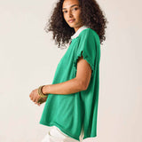 Woman wearing a green top with a plain background