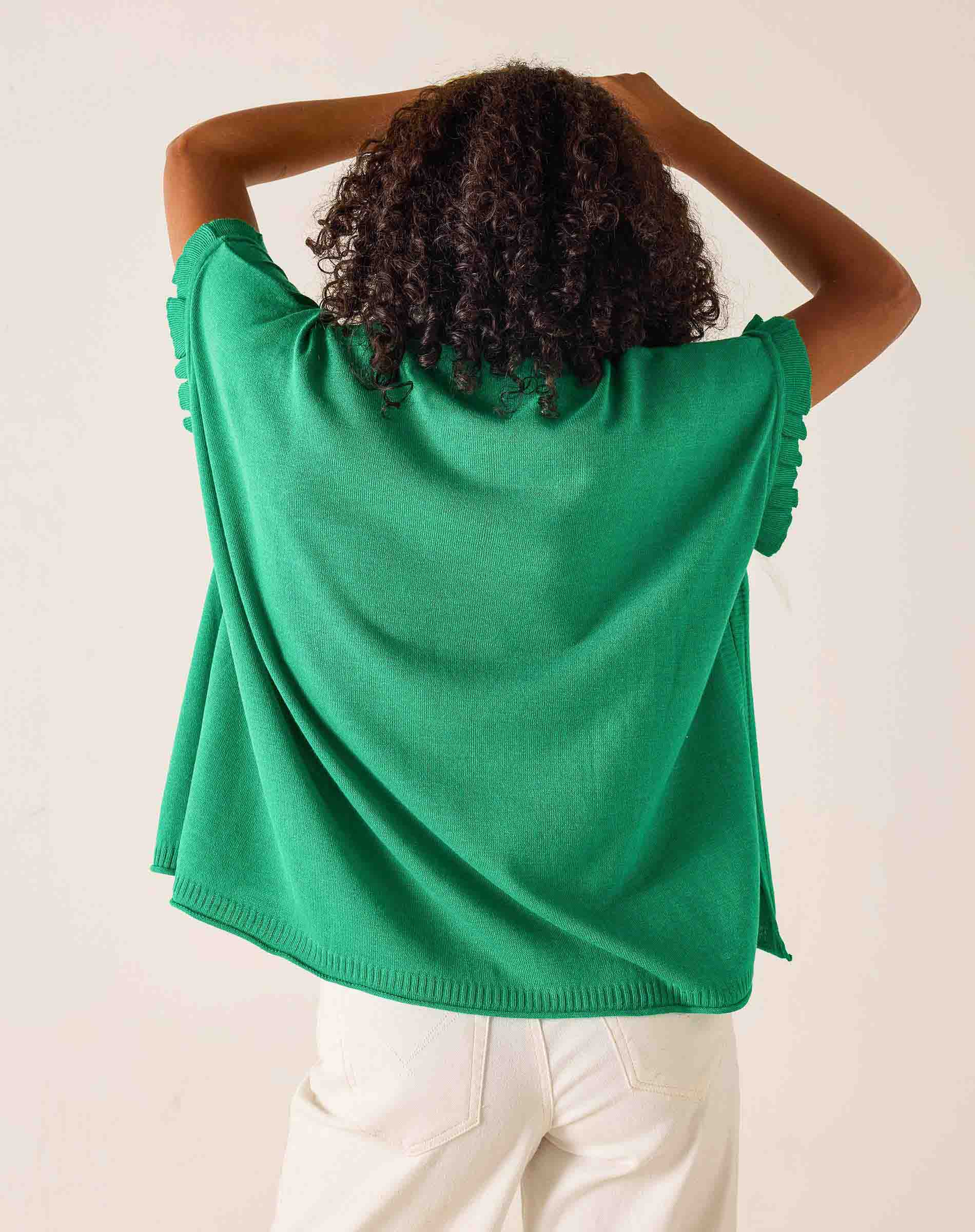 Person wearing a green sweater with a plain background