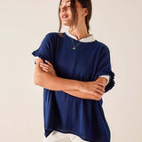 Woman wearing a navy blue sweater with rolled-up sleeves on a beige background