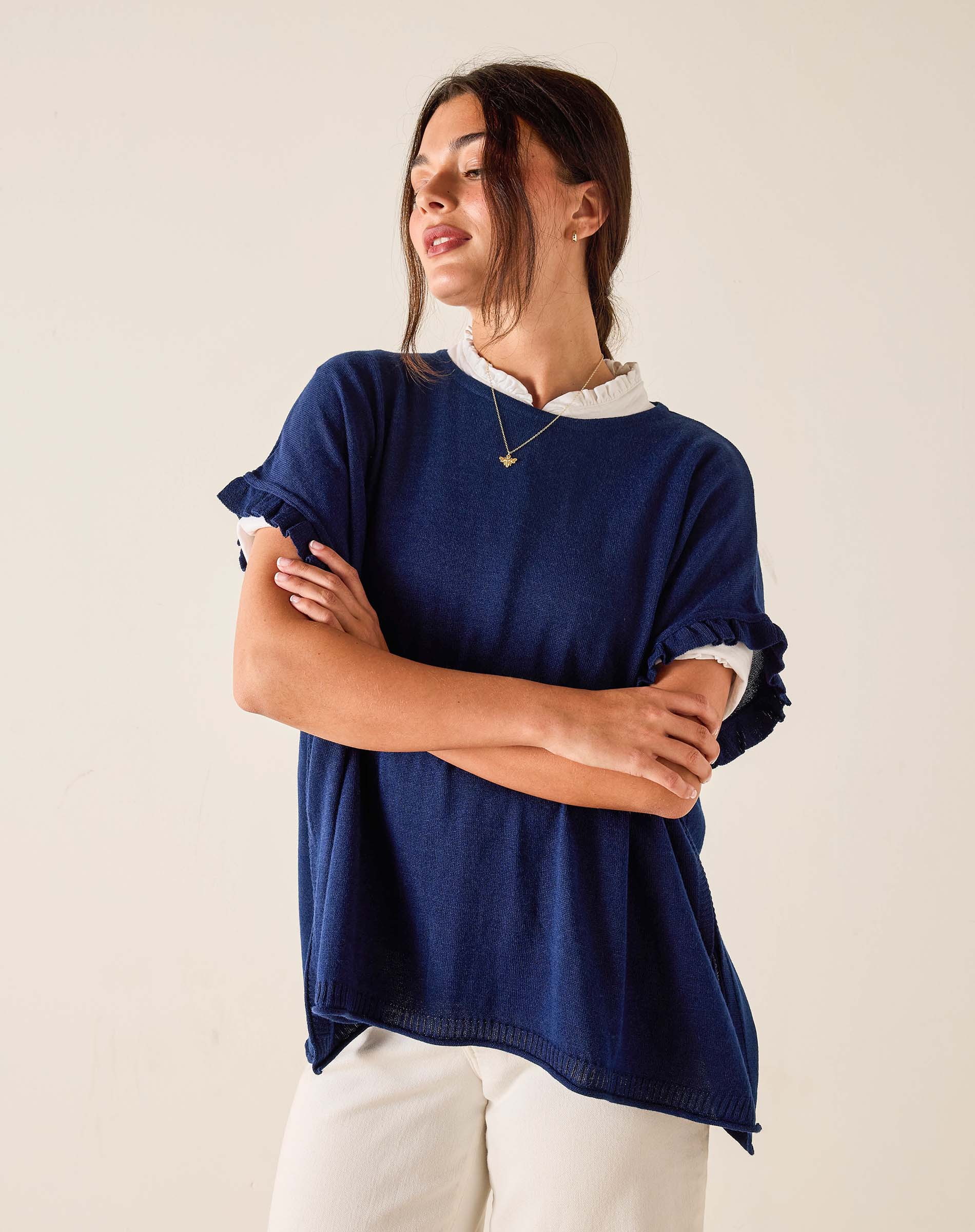 Woman wearing a navy blue sweater with rolled-up sleeves on a beige background