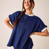 Woman wearing a blue poncho over a white shirt against a plain background