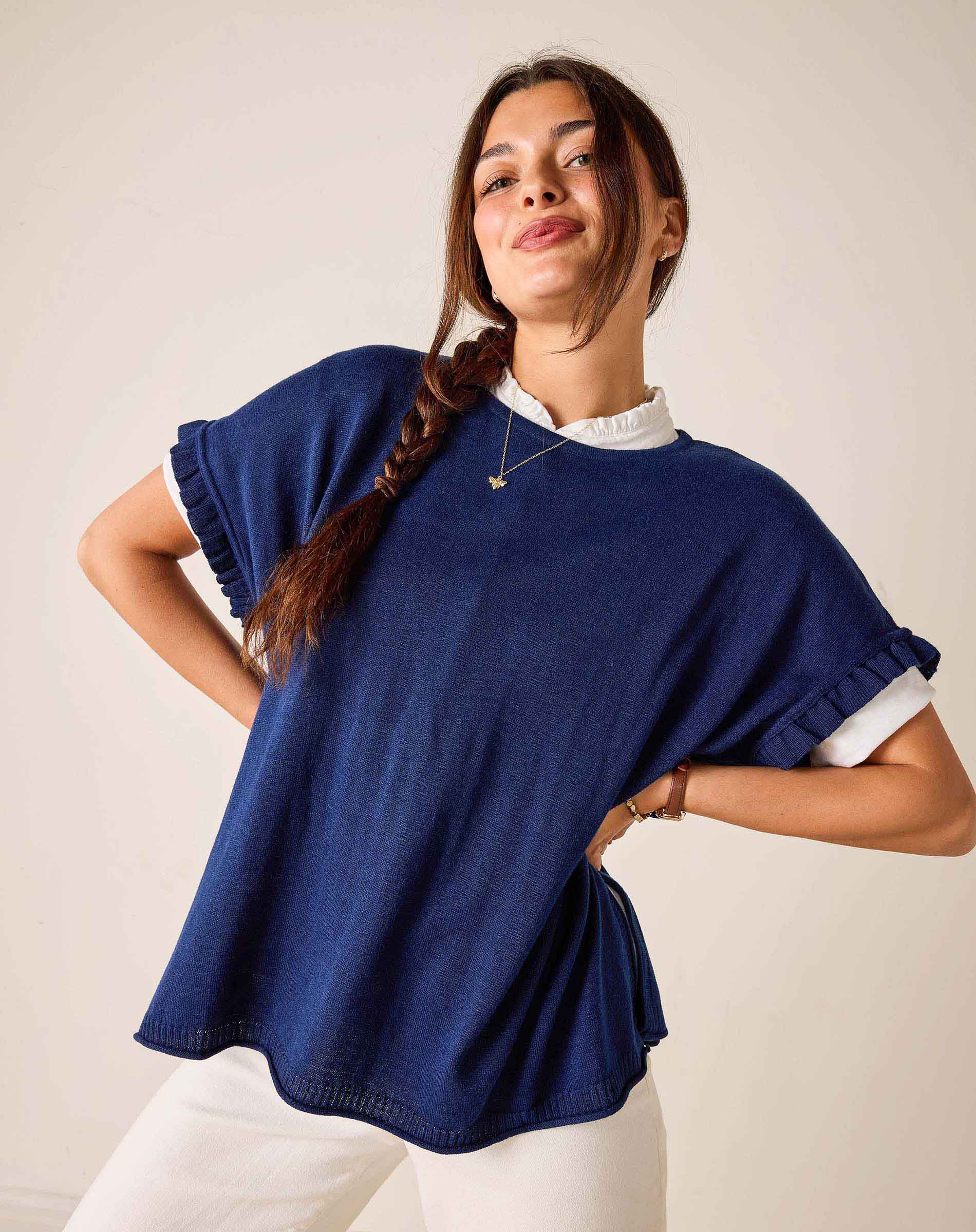 Woman wearing a blue poncho over a white shirt against a plain background
