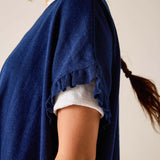 Person wearing a blue cardigan over a white shirt with a neutral background