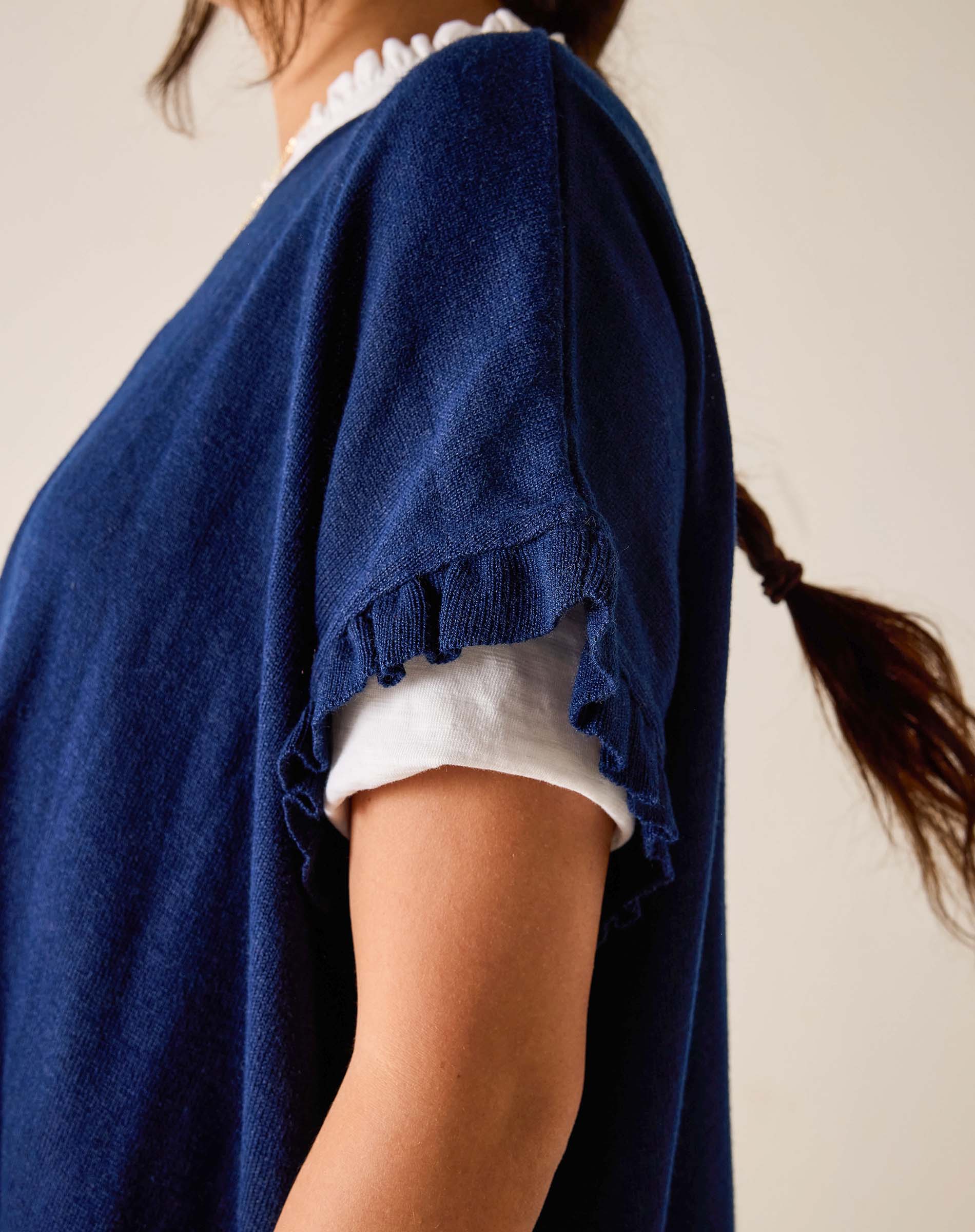 Person wearing a blue cardigan over a white shirt with a neutral background