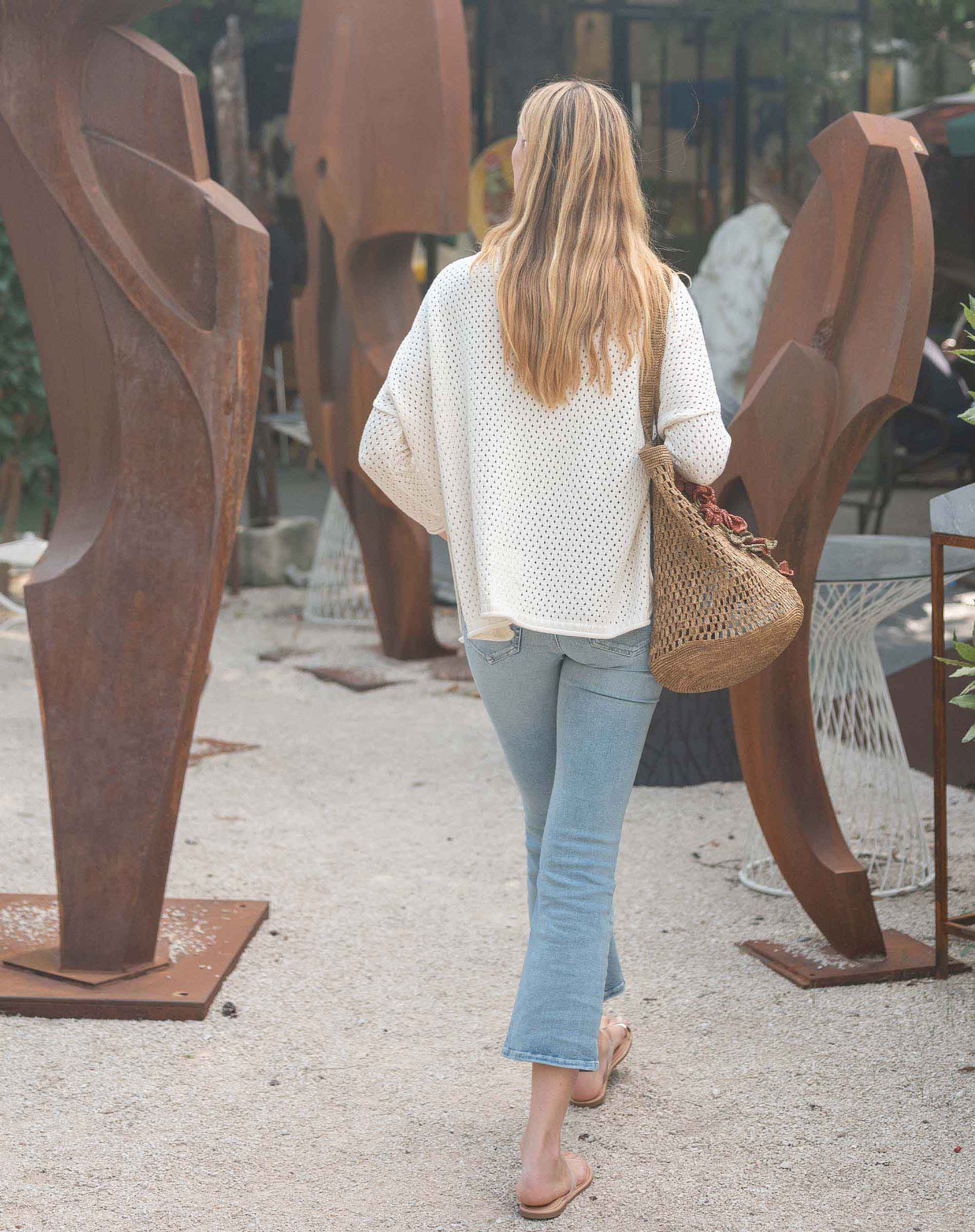 Woman walking past large metal sculptures in an outdoor setting