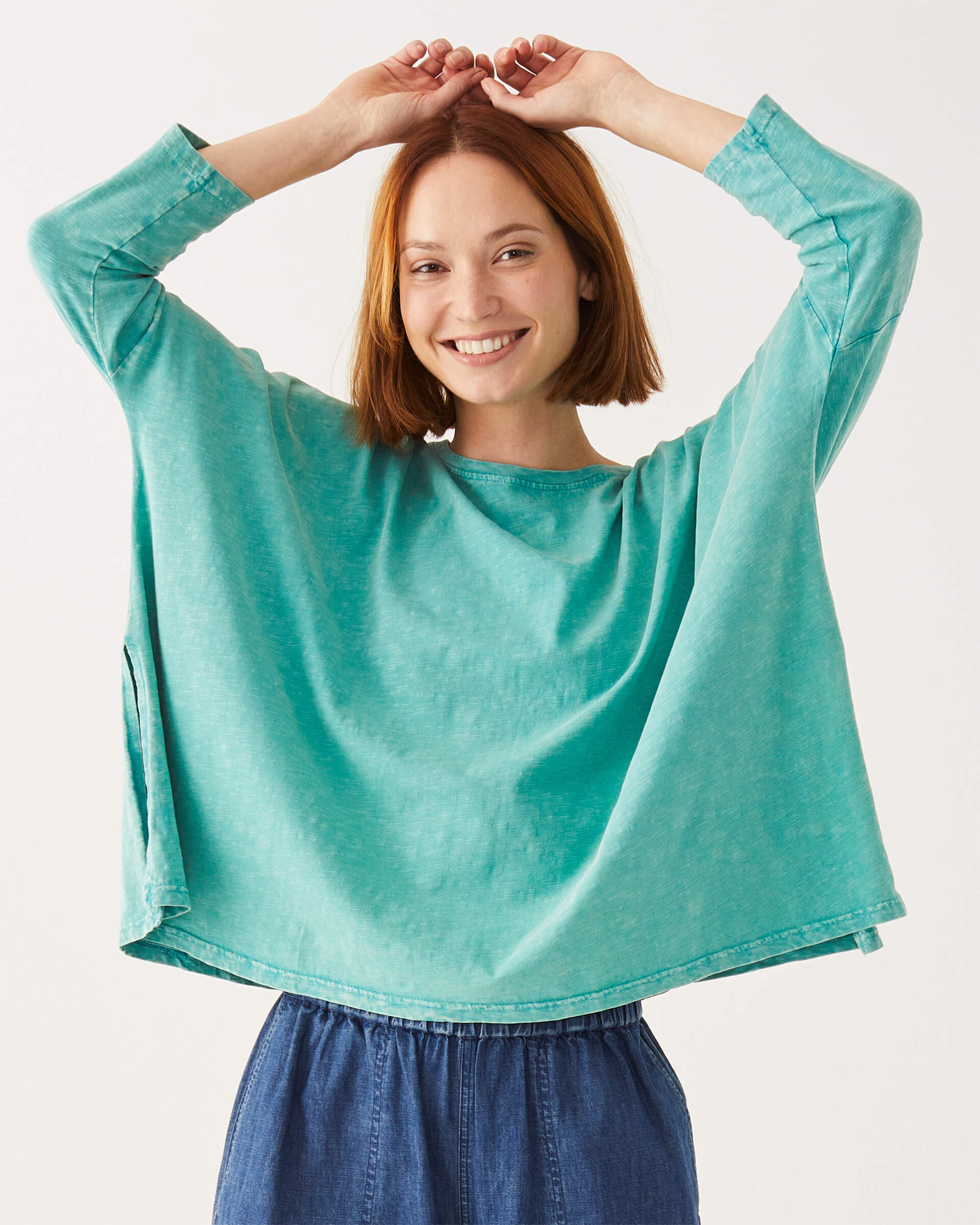 female wearing greenish blue long sleeve tee shirt with split sides on a white background