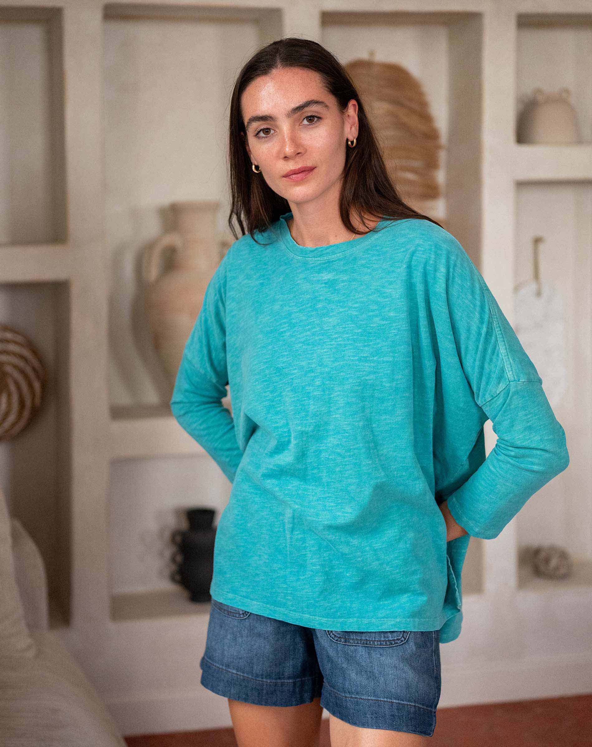 Woman wearing a green top and denim shorts in living room