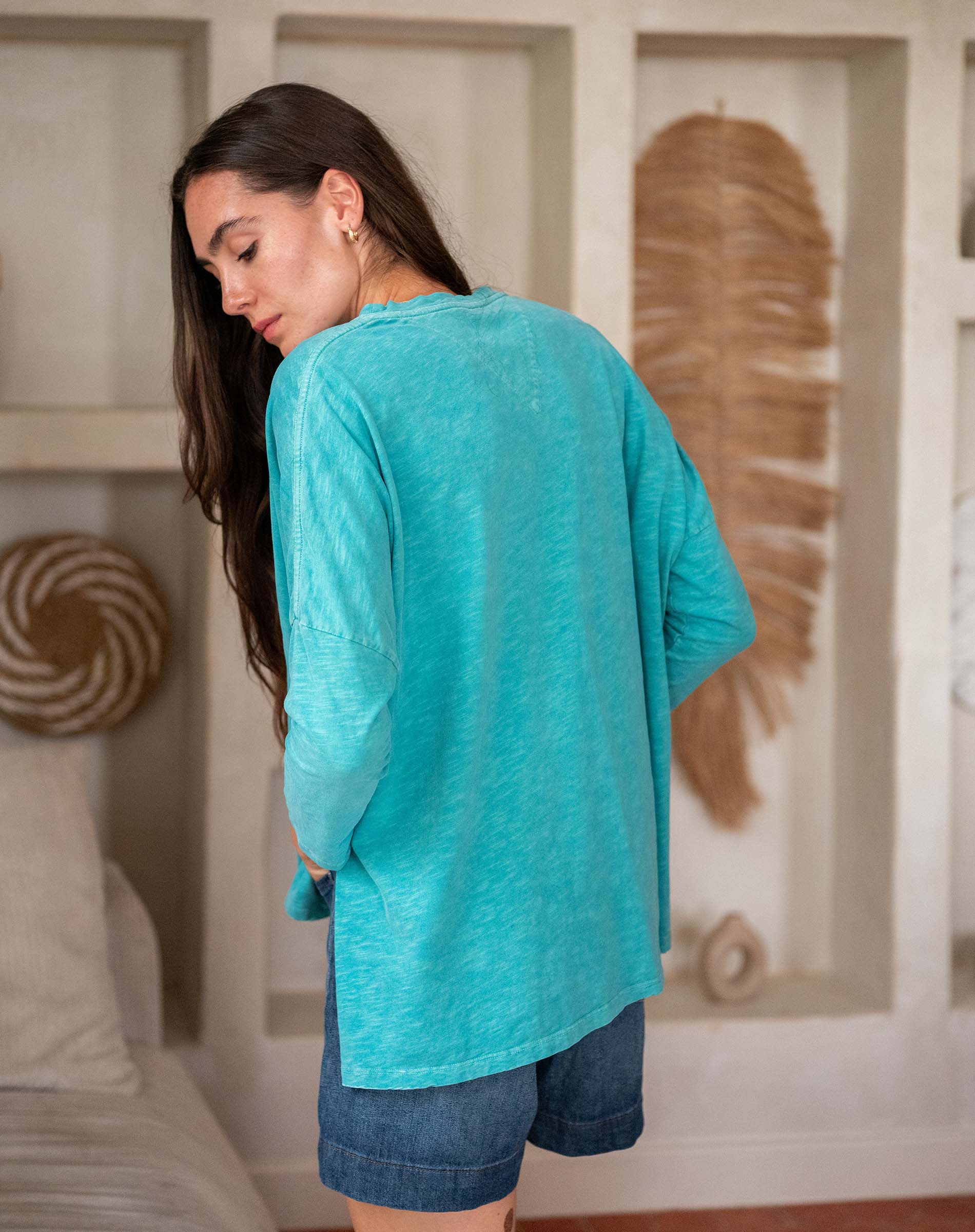 Woman wearing a green top and denim shorts in living room