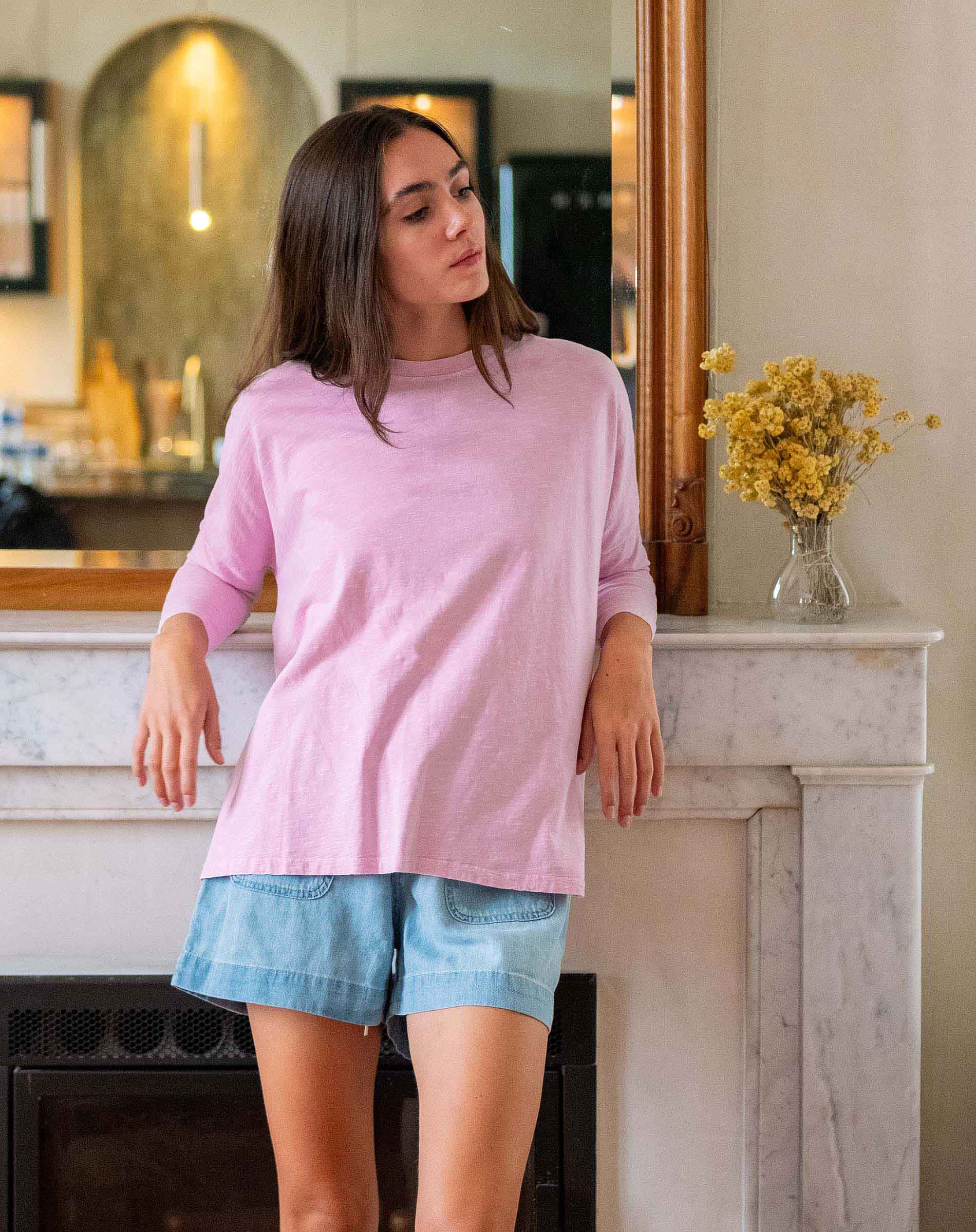 Woman wearing a pink top and denim shorts in living room