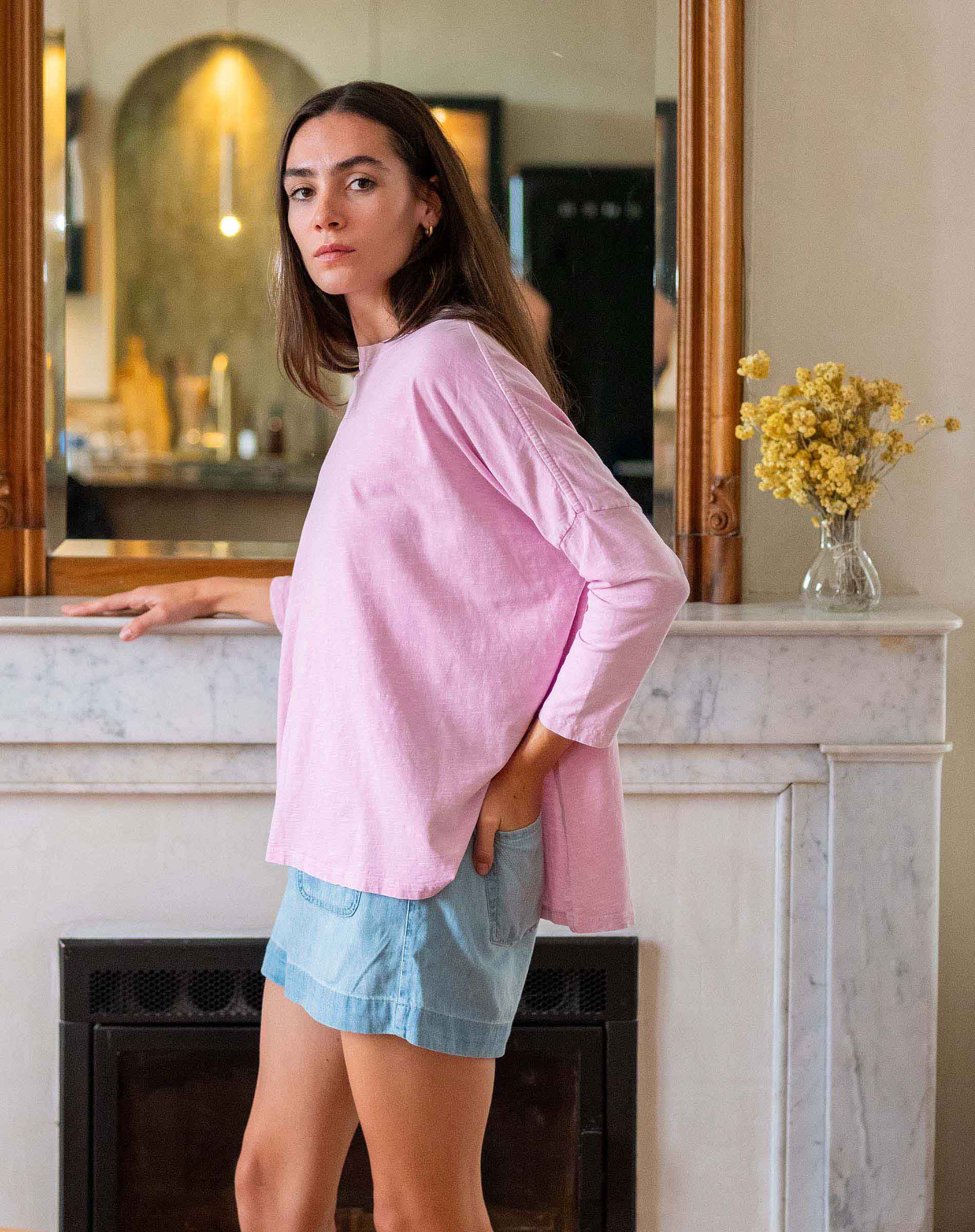 Woman wearing a pink top and denim shorts in living room