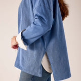 Side view of women's travel-friendly indigo sunwashed cotton tee featuring a relaxed fit and split hem detail.