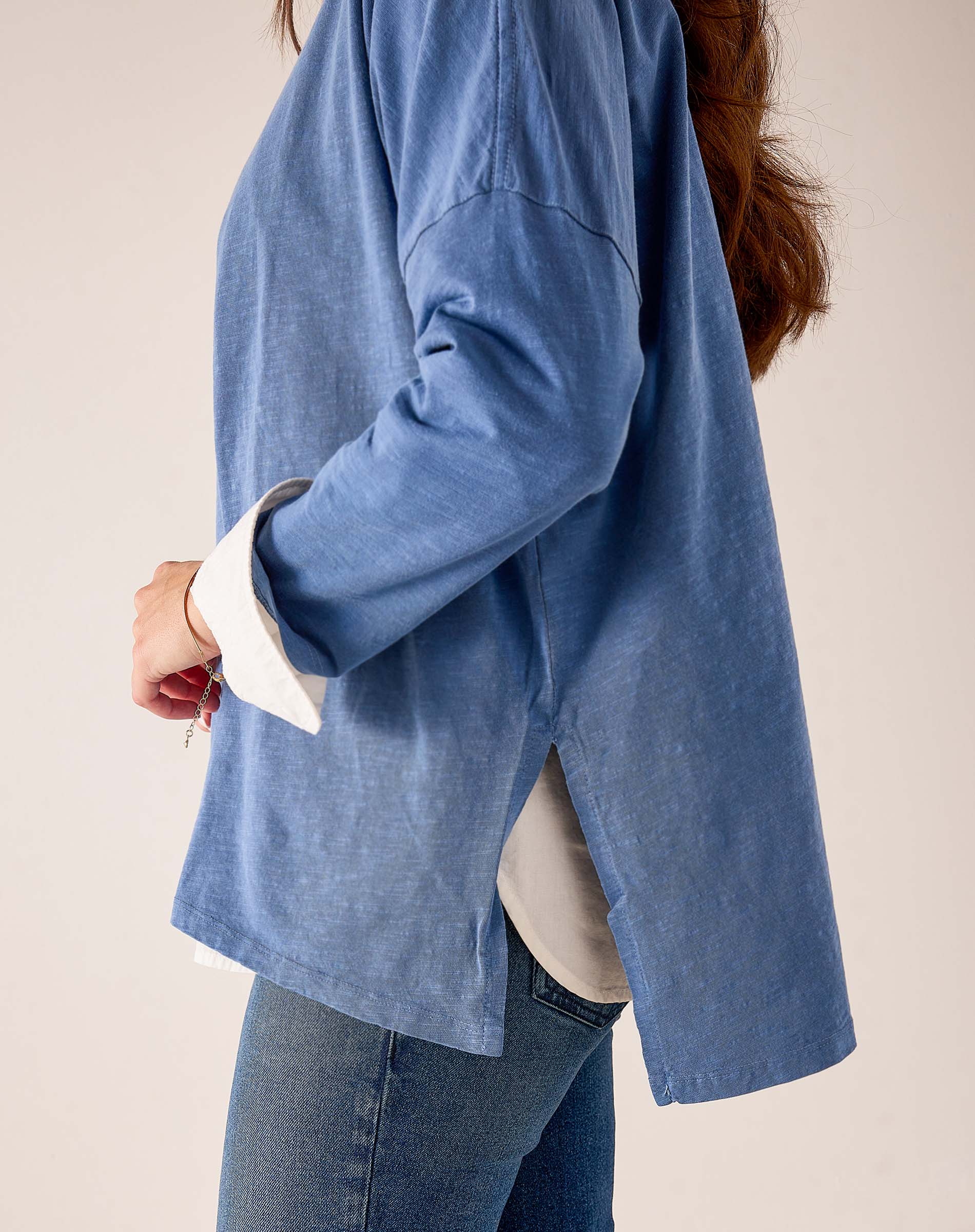 Side view of women's travel-friendly indigo sunwashed cotton tee featuring a relaxed fit and split hem detail.