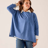 Indigo sunwashed cotton tee with a relaxed fit and wide neckline layered over a white collared shirt.