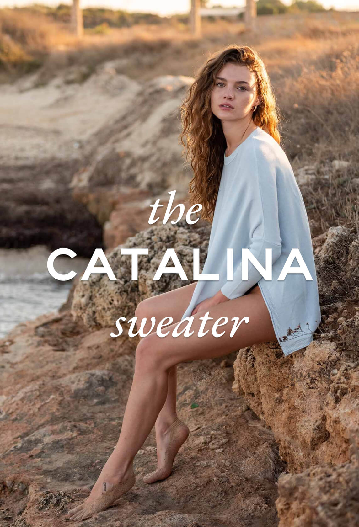 woman sitting on cliff near water wearing mersea catalina sweater