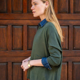 Woman wearing a green sweater and blue shirt against a wooden door background
