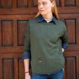Woman wearing a green sweater with a wooden door background