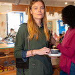 Two women in a store, one holding a coffee cup, with a blurred background