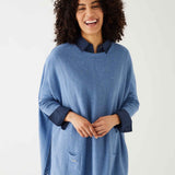 female wearing deep blue sweater with blue shirt cuffed with split sides on a white background