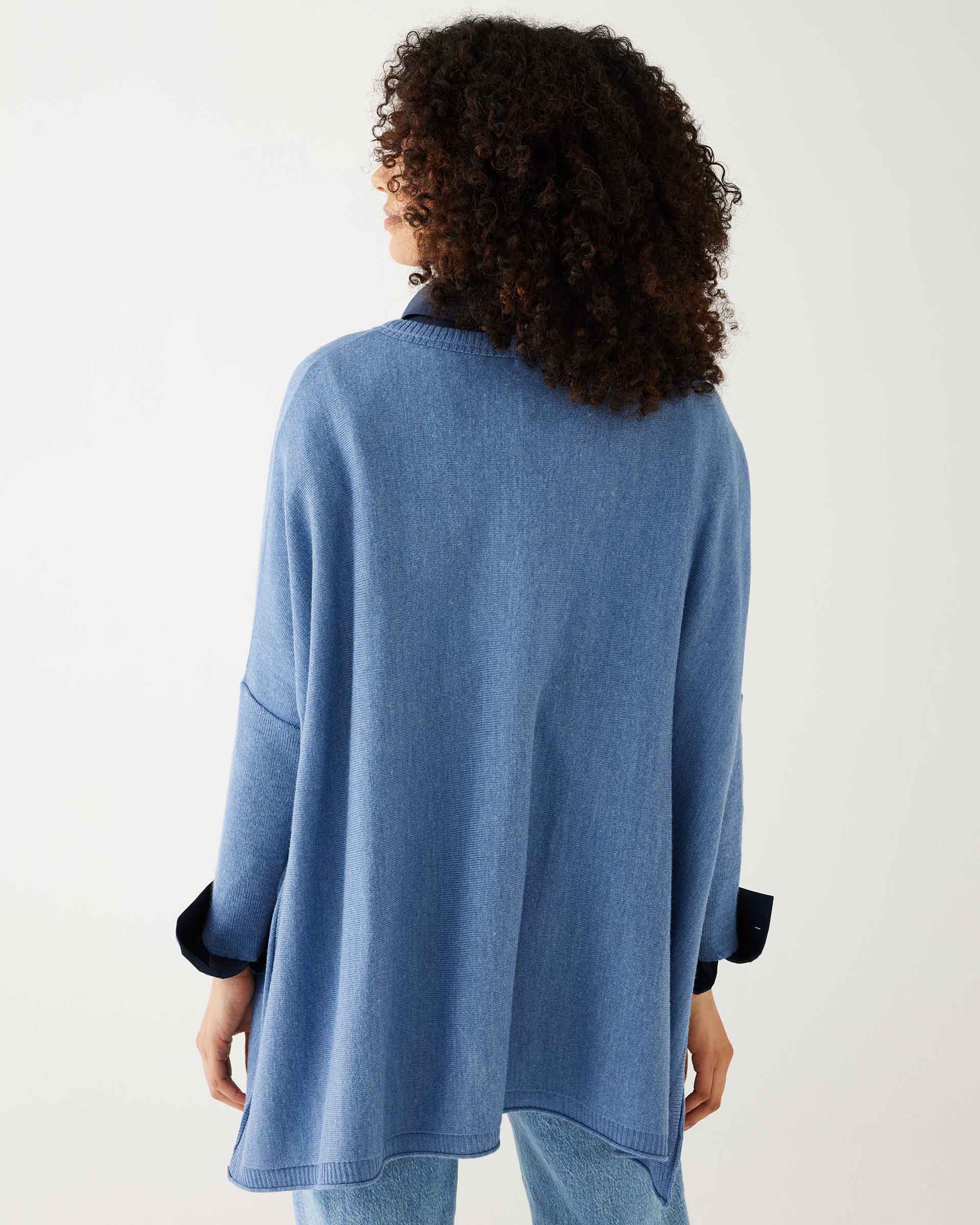 female wearing deep blue sweater with blue shirt cuffed backward on a white background