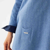 female wearing deep blue sweater with blue shirt cuffed at the sleeve on a white background